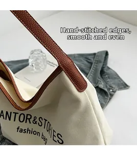 Detailed view of canvas tote bag with brown leather stitching and handle connection