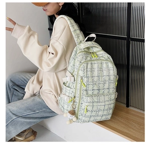 Détail du sac à dos à carreaux vert clair avec zip fluo et pendentif ours en peluche