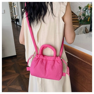 Pink quilted crossbody bag with puffy cloud design worn by a model in casual setting