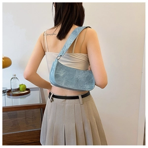 Detail of light blue PU leather underarm bag with vintage crackle texture and rivet strap