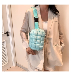 Close-up of mint green quilted puffer crossbody bag worn with a white casual suit blazer