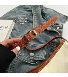 Detailed shot of adjustable brown leather shoulder strap with gold metal buckle on canvas bag