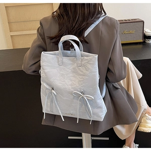 Detail of light blue PU backpack featuring unique wrinkled texture and long ribbon bows