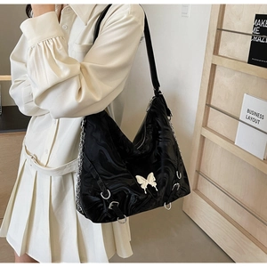Detail showing wave-textured black PU leather tote with 3D butterfly emblem and silver chain