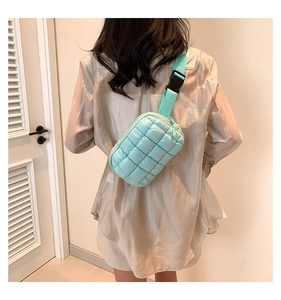 Detailed back view of a mint green quilted crossbody bag worn by a model in a room
