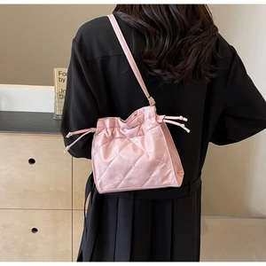 Detail of pink quilted PU leather bucket bag with drawstring closure and fine strap