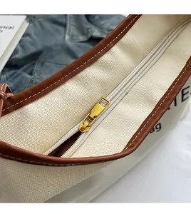 Detail of canvas tote bag with smooth golden metal zipper and brown leather trim accents