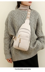 Close-up of cream PU leather crossbody bag with golden zippers and floral strap