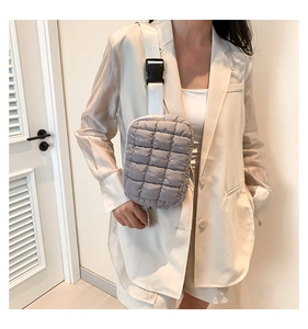 Close-up of a grey quilted puffer crossbody bag with adjustable nylon strap and plastic buckle