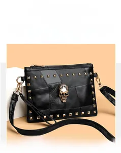 Close-up of black leather crossbody bag featuring gold studs and a skull centerpiece