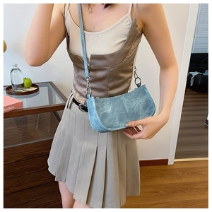 Detail showing light blue PU shoulder bag with silver hardware on a wooden table