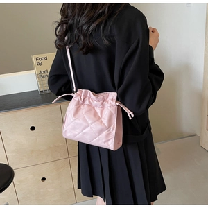 Detailed view of pink quilted PU leather crossbody bag with drawstring closure on model