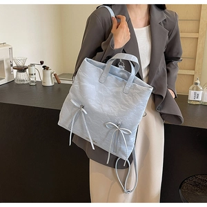 Detailed close-up of light blue PU leather backpack with bow ribbons and pleated texture