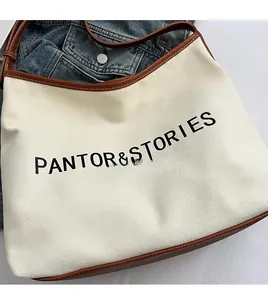Detail shot of the cream canvas tote with brown leather trim and fashion bag logo design