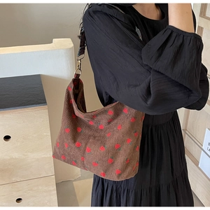 Detail of strawberry print corduroy shoulder bag with metal D-ring and wide strap