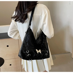 Detail of black Hobo bag with wave texture, butterfly charm and metal chain accessory
