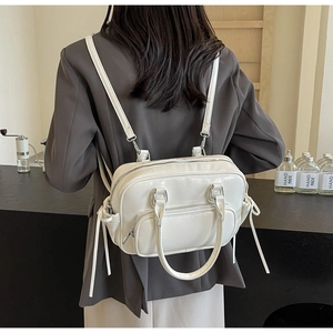 Detailed view of a white glossy PU leather backpack with silver hardware on a desk