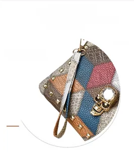 Detail of color-block wristlet with gold studs and crystal skull metallic emblem