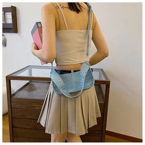 Detail view of light blue crossbody bag featuring wide studded strap in vintage street style