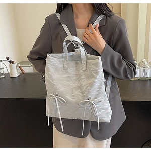 Detail of metallic silver pleated PU backpack with bow accents and dual zippers