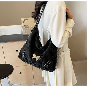Detail of black glossy shoulder bag with silver butterfly buckle and marble texture