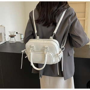 White minimalist leather backpack shown on back with silver hardware and top handle