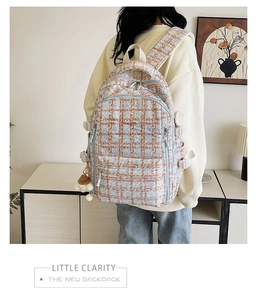Détail du sac à dos en velours côtelé à carreaux avec double zip et breloque boule tricotée