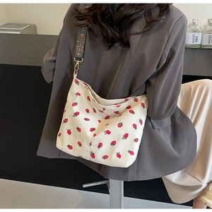 Detail of corduroy tote bag with red strawberry print and ethnic floral wide strap