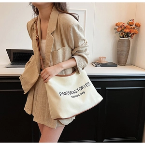 Detailed close-up of a minimalist canvas tote bag with leather trim and fashion lettering
