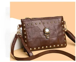 Close-up of brown leather bag with golden square rivets and skull crystal embellishment