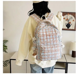 Détail d'un sac à dos en velours côtelé à carreaux bleus avec double zip et gri-gri champignon