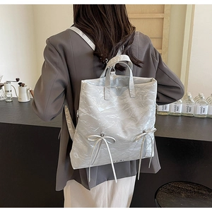 Detailed view of white pleated PU leather backpack with decorative bows on a lifestyle background
