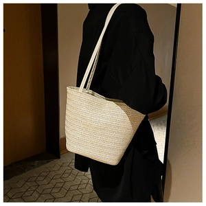 Detailed view of the woven straw tote bag with elegant herringbone texture and white strap