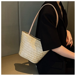 Close-up of woven straw tote bag with V-shaped chevron pattern and leather shoulder strap