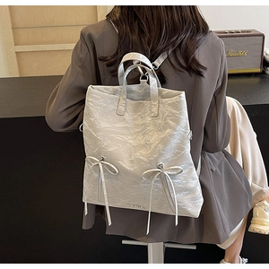 Close-up of light gray PU leather backpack featuring unique pleat texture and ribbon detail