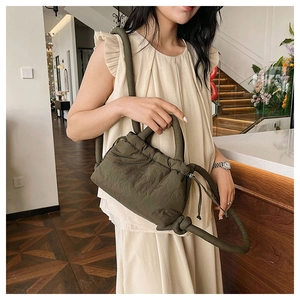 Detail of olive green puffy handbag with drawstring closure and thick padded handle
