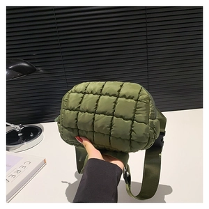 Army green quilted crossbody bag in ripstop nylon held by a hand in a modern interior