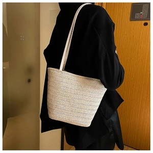 Detail of hand-woven beige and white chevron straw tote bag with thin white straps