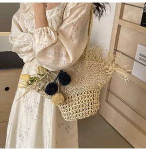 Dettaglio della borsa in paglia con frange decorative e ciondoli pom-pom in una scena reale