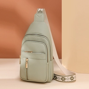 Green water-resistant crossbody bag with floral ethnic strap and golden zippers