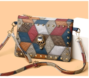 Detail of colorful patchwork crossbody bag featuring gold rivets and a crystal skull charm