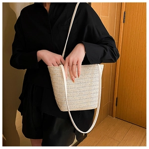 Close-up of beige woven tote bag with fine chevron texture and white shoulder strap