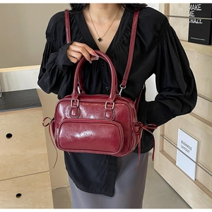 Detail showing wine red glossy faux leather texture and drawstring bow on the handbag