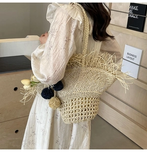 Dettaglio della borsa tote in paglia intrecciata con frange e nappine su legno