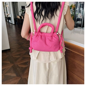 Detail view of fluorescent pink quilted nylon drawstring backpack worn by model