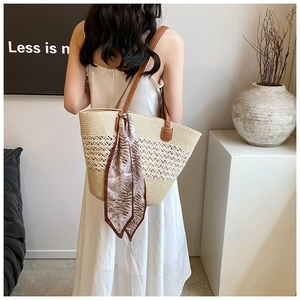 Close-up of beige woven straw tote bag with hollow knit design and brown leather straps