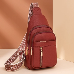 Deep red pebbled leather crossbody bag with multiple zippers and patterned wide strap