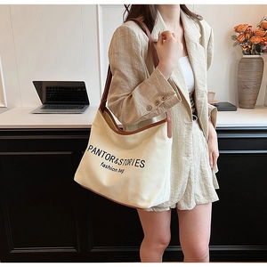 Close-up of a large canvas shoulder bag with brown leather trim and PANTOR text logo