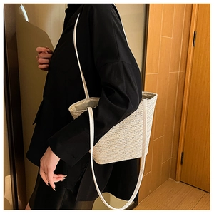 Detail of cream woven tote bag with white leather straps and elegant V-shaped texture
