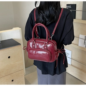 Close-up of vintage burgundy PU leather backpack with dual-handle and elegant bow details